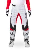 Alpinestars Limited Edition Techstar Deep Hose, Motocross-Hose, Schwarz, Weiß und High Red, getragen mit passendem rotem Jersey, weiß-schwarzen Handschuhen und Stiefeln, mit weißen Frontpanels, roten Akzenten an den Beininnenseiten, schwarzen Seitenpanels, Alpinestars-Logos auf den Oberschenkeln und laserperforierten Details zur Belüftung.