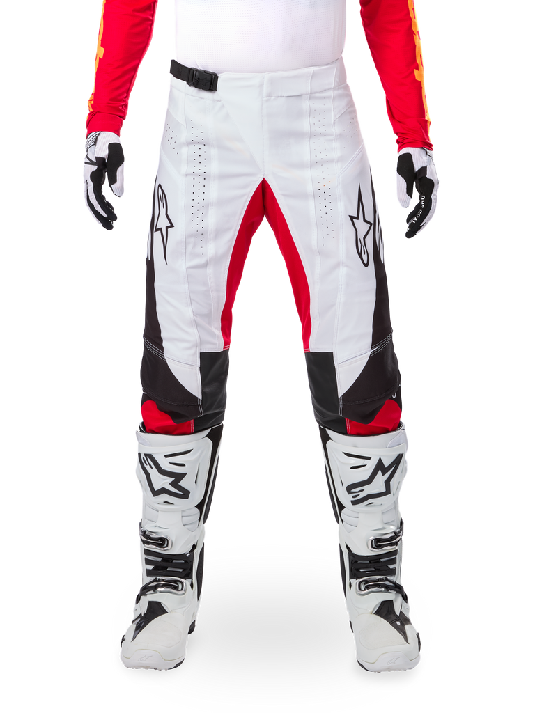 Alpinestars Limited Edition Techstar Deep Hose, Motocross-Hose, Schwarz, Weiß und High Red, getragen mit passendem rotem Jersey, weiß-schwarzen Handschuhen und Stiefeln, mit weißen Frontpanels, roten Akzenten an den Beininnenseiten, schwarzen Seitenpanels, Alpinestars-Logos auf den Oberschenkeln und laserperforierten Details zur Belüftung.