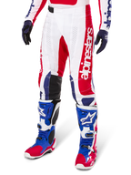 Alpinestars Limited Edition Techstar Fortitude Motocross-Hose, rot-weiß-blaues Farbschema, getragen mit passenden Motocross-Stiefeln und Handschuhen, mit vertikalem Alpinestars-Branding, athletische Passform für den Offroad-Rennsport