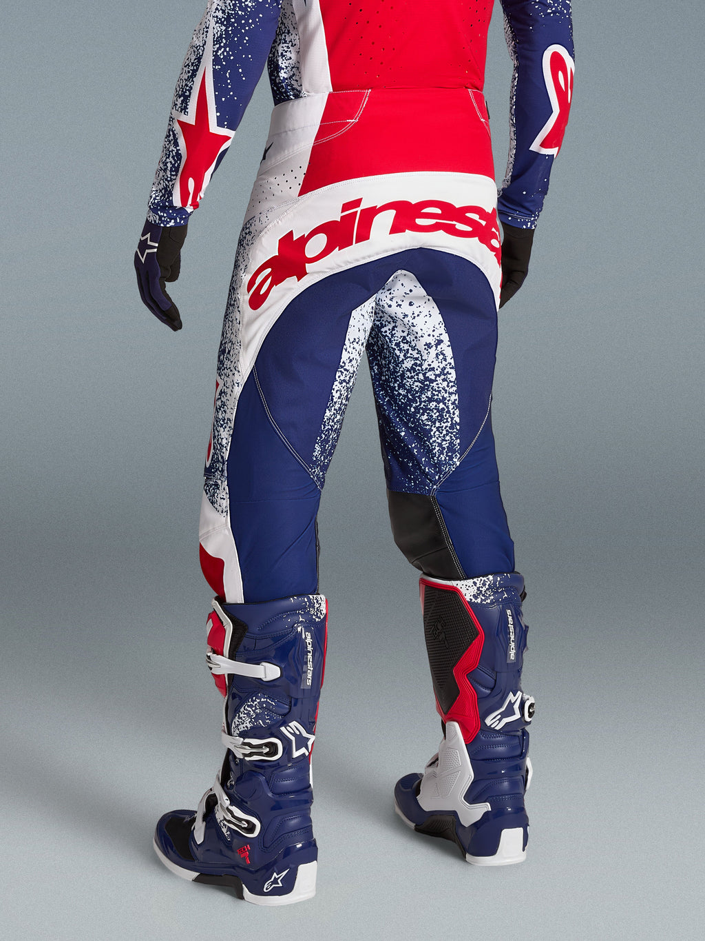 Alpinestars Techstar Unity Bekleidungsset, rot-blaue Motocross-Ausrüstung, athletische Passform und Logo auf der Rückseite.