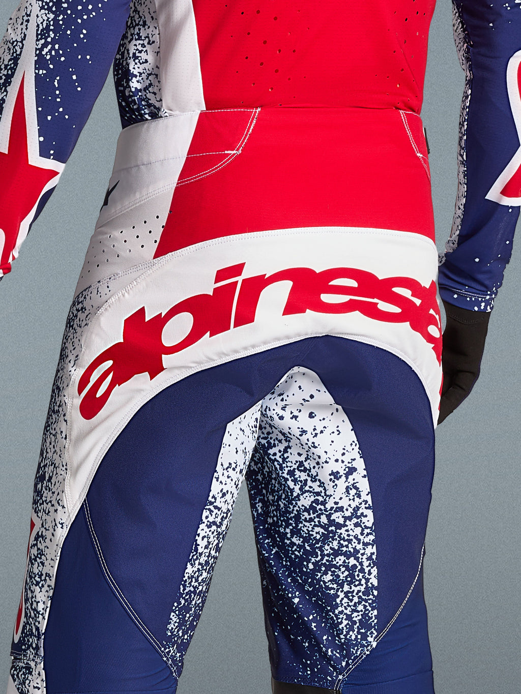 Alpinestars Techstar Unity Bekleidungsset Limited Edition, Motocross-Hose in Rot, Blau und Weiß mit rotem Logo-Schriftzug.