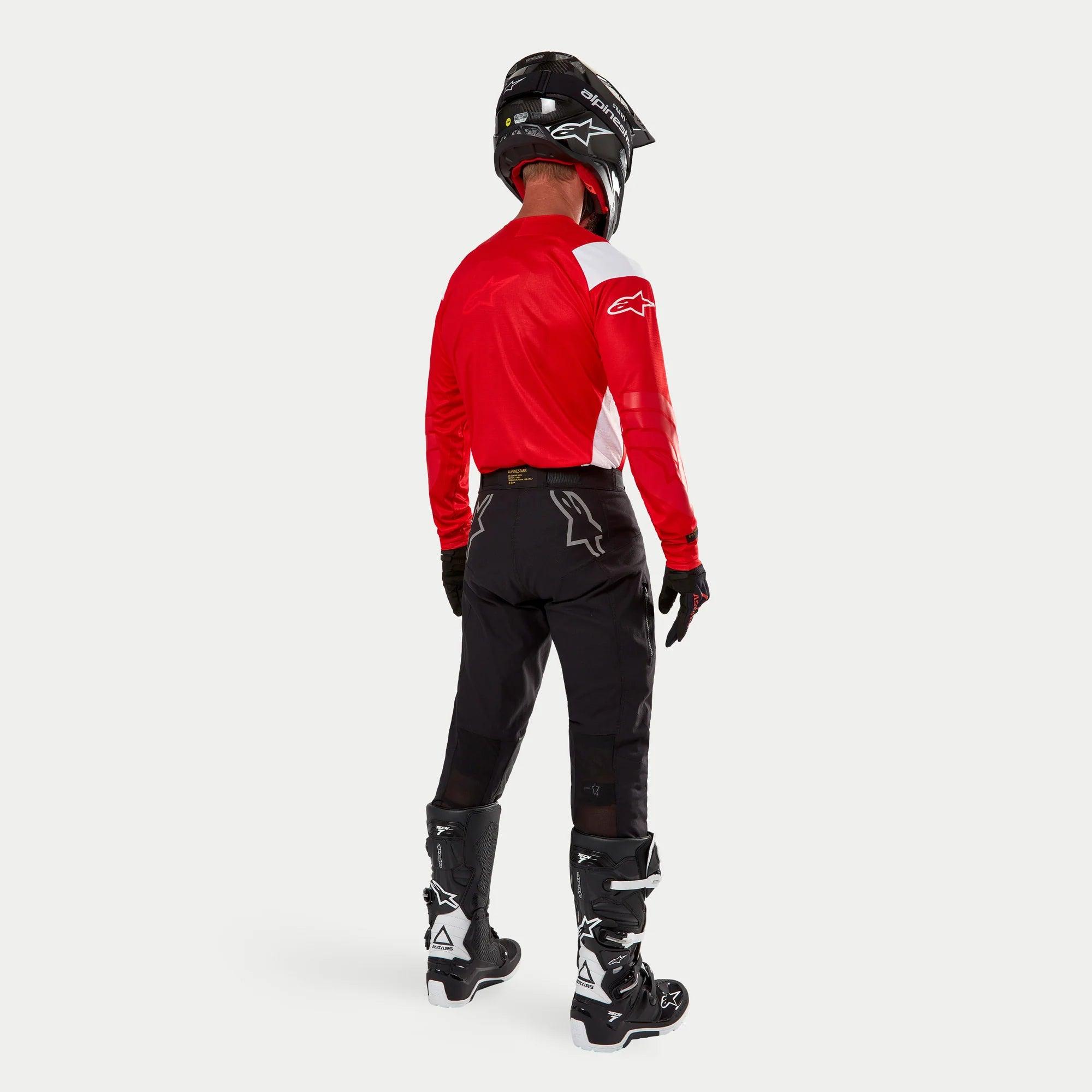 Alpinestars Techdura Hose, Enduro-Offroad-Hose, Schwarz, Rückansicht getragen von einem Fahrer mit einem rot-weißen Trikot und schwarz-weißen Stiefeln, mit weißen Stern-Logos auf der Rückseite und strapazierfähiger technischer Stretch-Konstruktion.