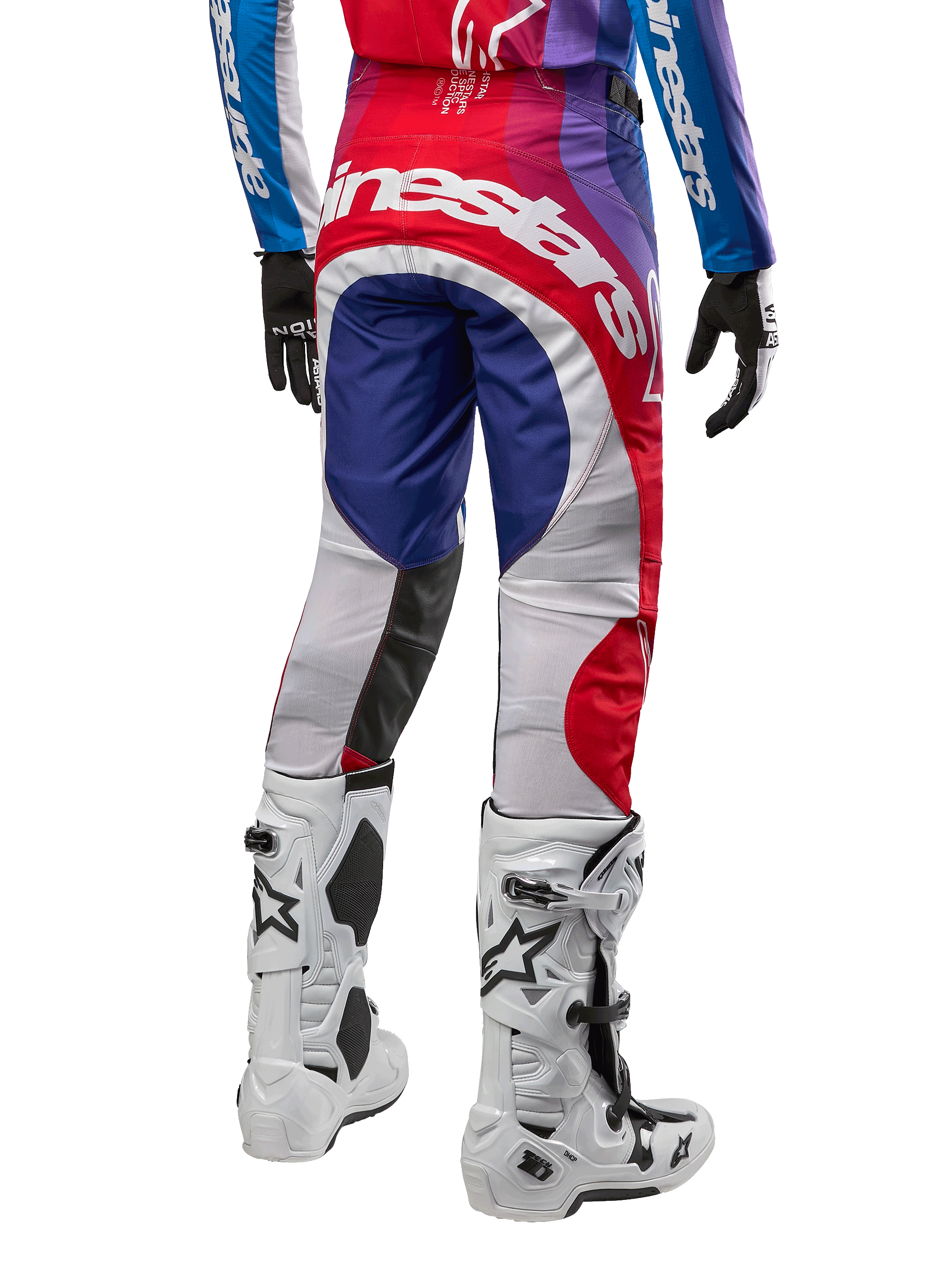 Alpinestars 2024 Techstar Pneuma Hose, Motocross-Hose, Blu Mars Rot Weiß, Rückansicht getragen mit passendem Trikot und weißen Stiefeln, auffälliges weißes Branding auf dem Gesäß, mehrfarbige Einsätze, professionelle Motocross-Rennausrüstung