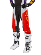 Alpinestars 2024 Techstar Ocuri Hose, Motocross-Hose, Hot Orange, Schwarz und Weiß mit gelber Sterngrafik, getragen mit lila Trikot und weißen Stiefeln, strapazierfähige Performance-Ausrüstung für den Offroad-Wettkampf