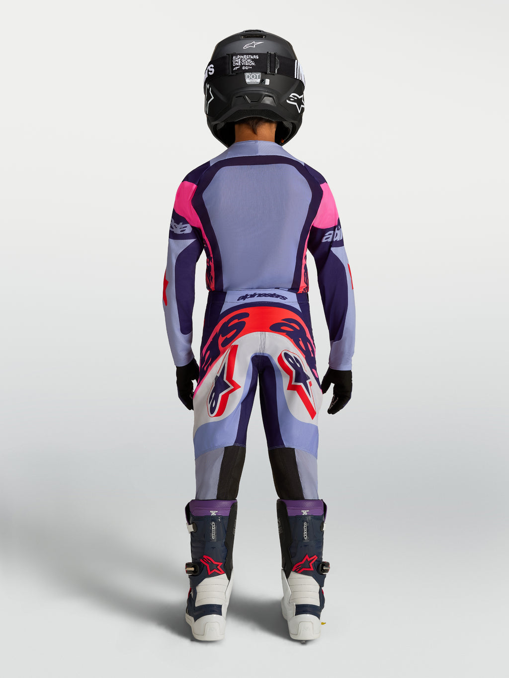 Alpinestars Jugend Supertech Dyna Hosen, Motocross-Rennhose für Kinder, Hellviolett und Lila, Rückansicht am jungen Fahrer mit Helm und Stiefeln, strapazierfähige MX-Bekleidung