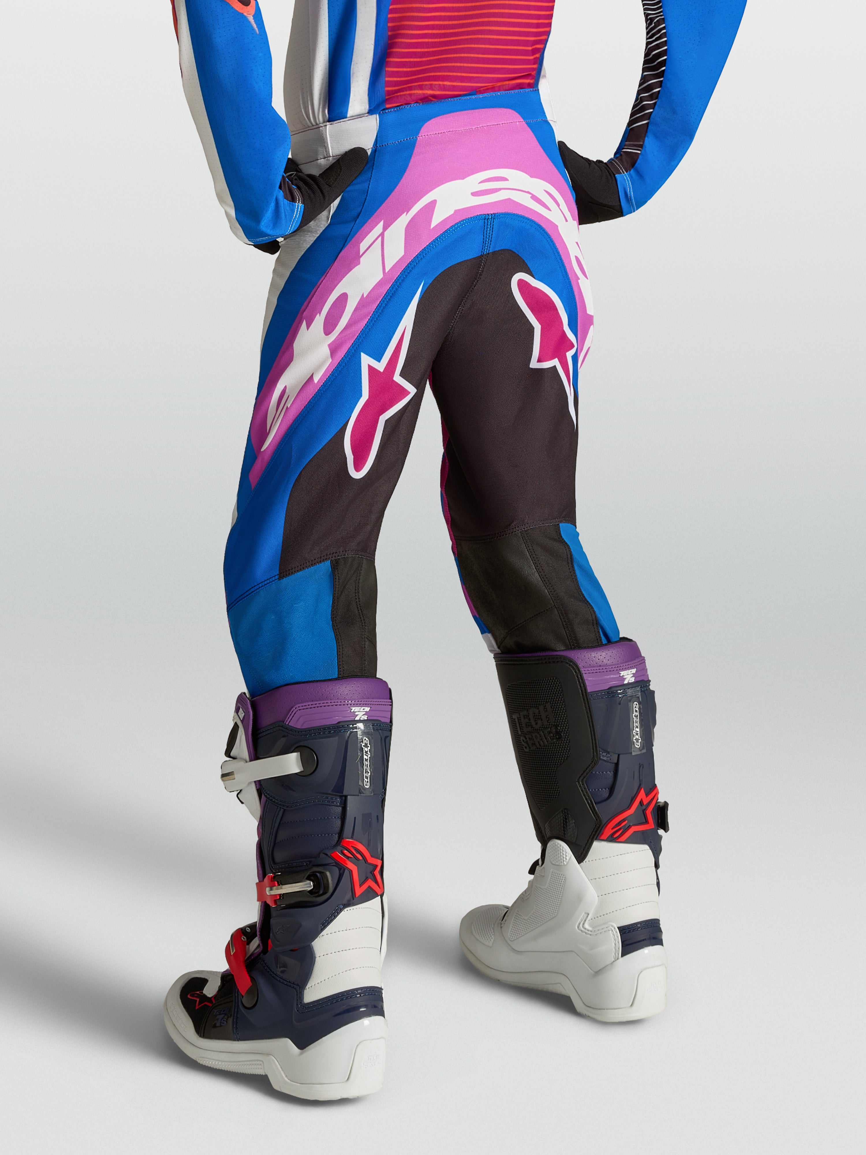 Alpinestars Jugend Supertech Maven Hose, Motocross-Rennhose für Kinder, Blau, Pink und Weiß, athletische Passform mit Stretch-Materialien für optimale Bewegungsfreiheit bei Geländefahrten, Rückansicht am Model mit Motocross-Stiefeln