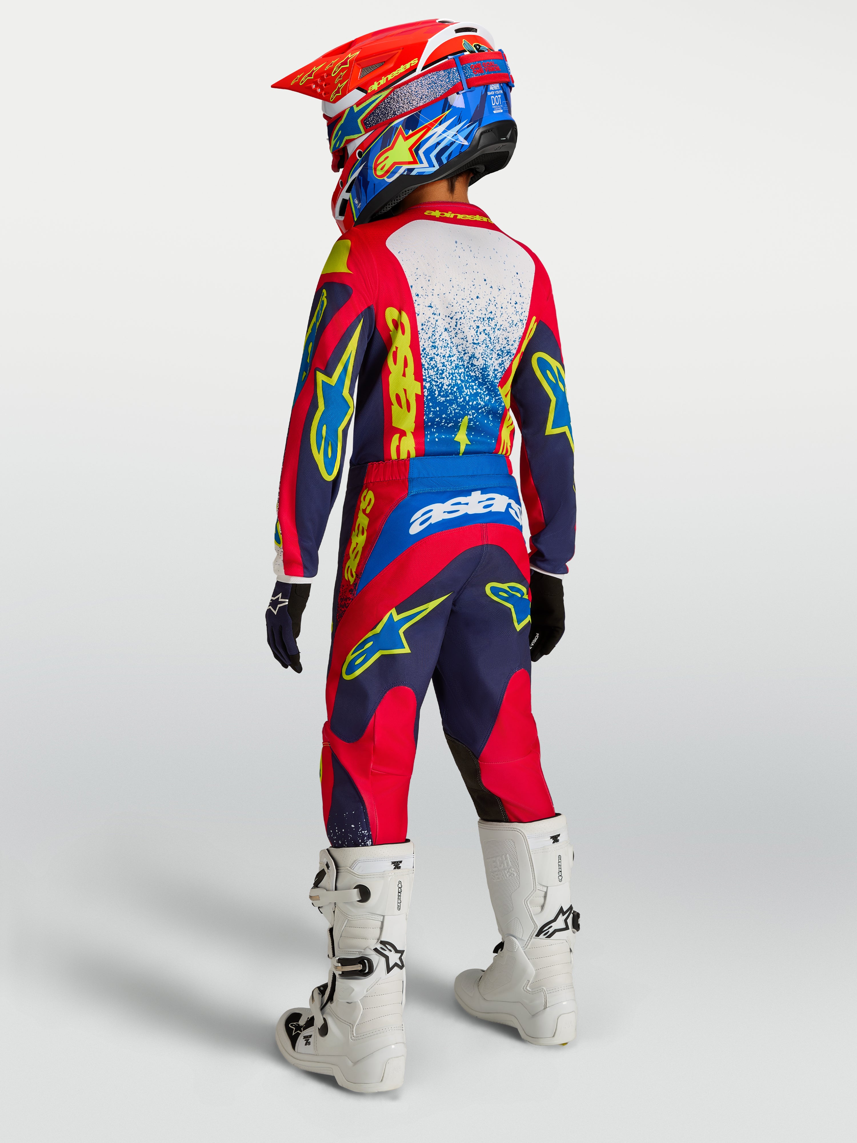 Alpinestars Jugend Fluid Drag Hose, Motocross-Hose in Dunkelblau und Feuerrot mit verstärktem Sitz und weißen Rennstiefeln.