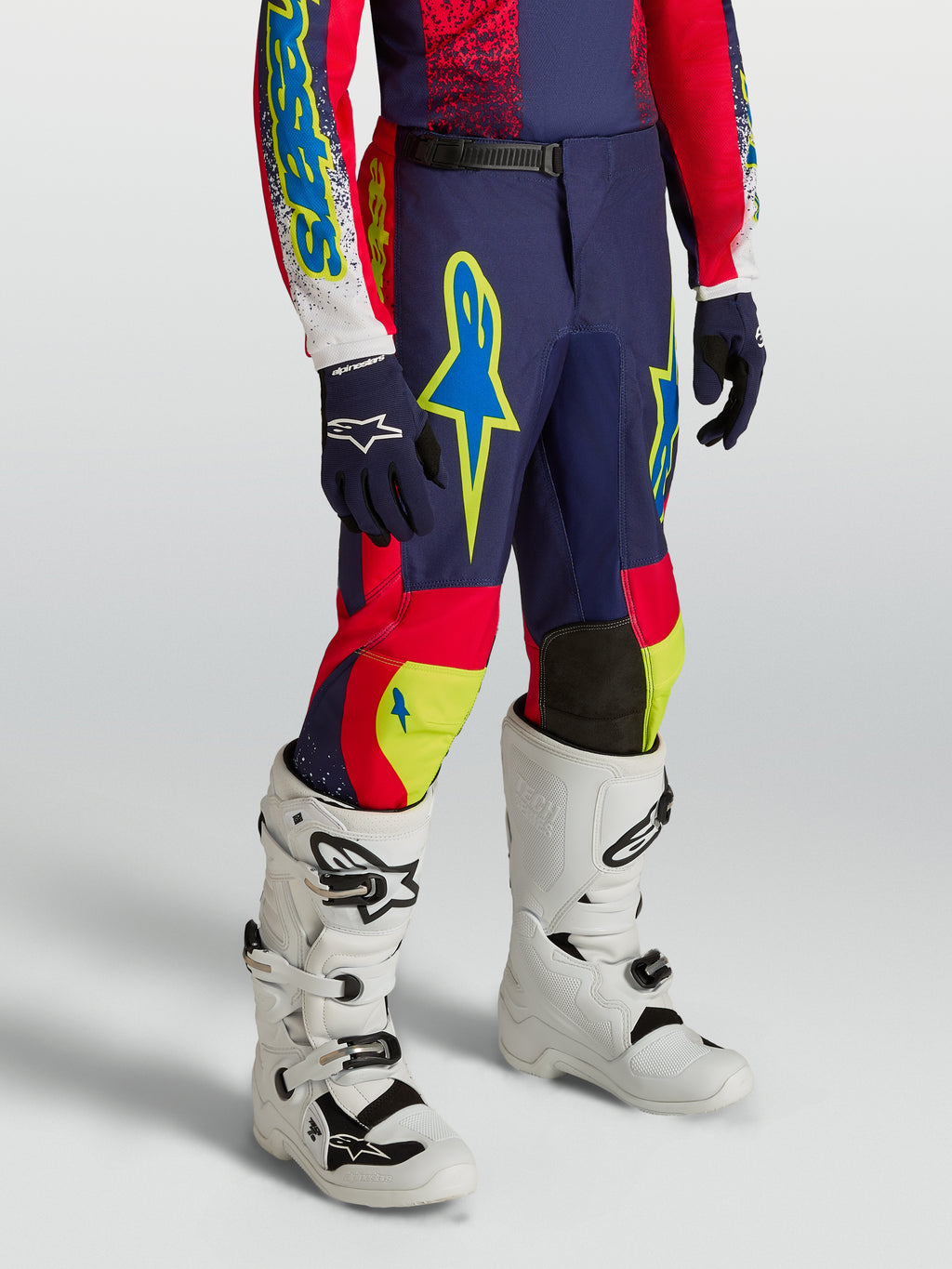 Alpinestars Jugend Fluid Drag Hose, navyblaue und rote Motocross-Ausrüstung mit Neon-Akzenten und weißen Stiefeln.