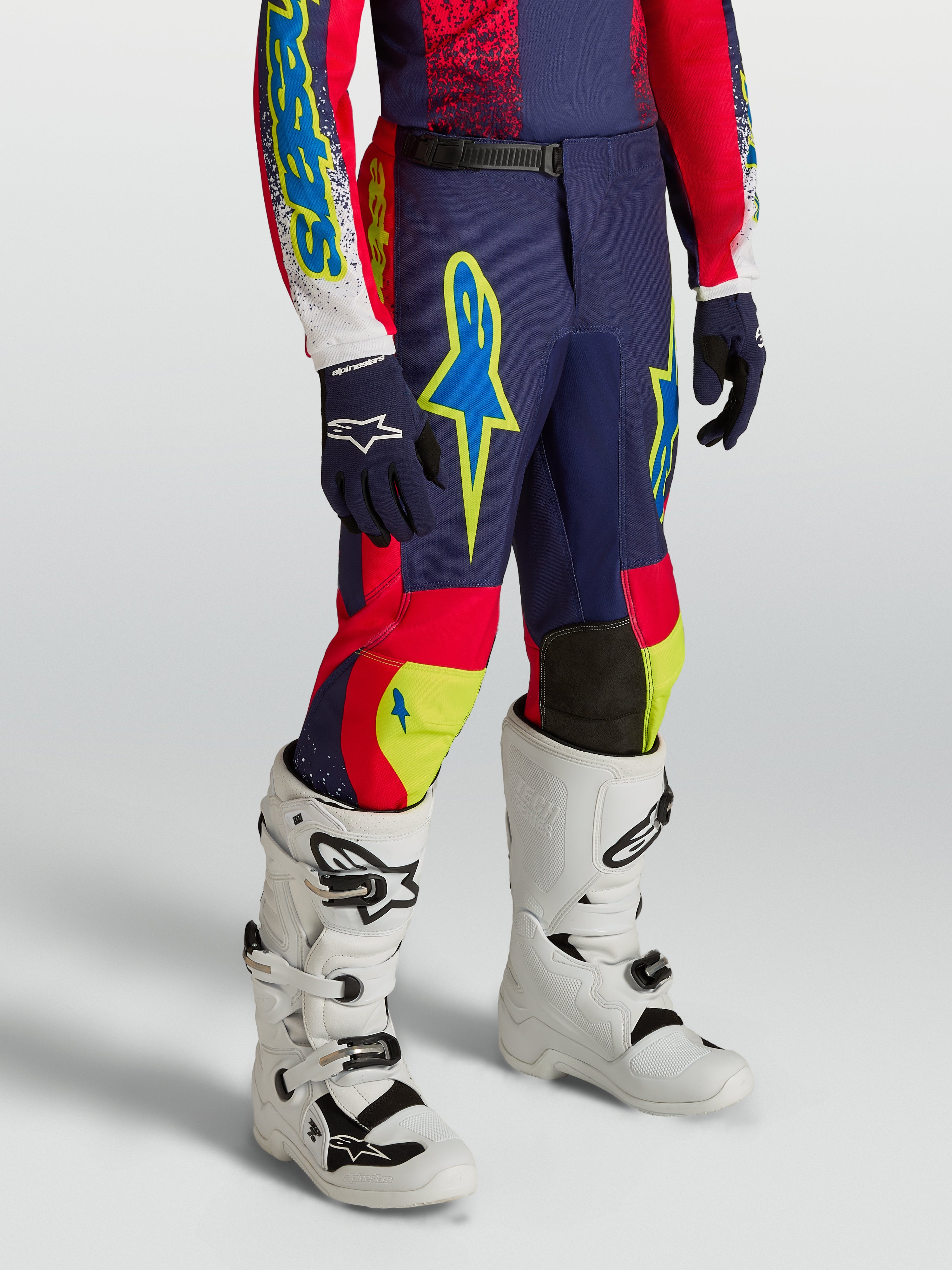 Alpinestars Jugend Fluid Drag Hose, navyblaue und rote Motocross-Ausrüstung mit Neon-Akzenten und weißen Stiefeln.
