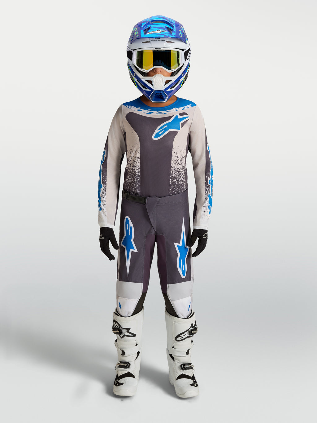 Alpinestars Fluid Drag Jugend-Hose, Motocross-Ausrüstung, Grau und Blau, Polygewebe, weiße Motorradstiefel.