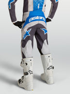 Alpinestars Fluid Drag Jugend-Hose 2027 in Grau und Blau, Motocross-Hose in der Rückansicht mit weißen Motorradstiefeln.