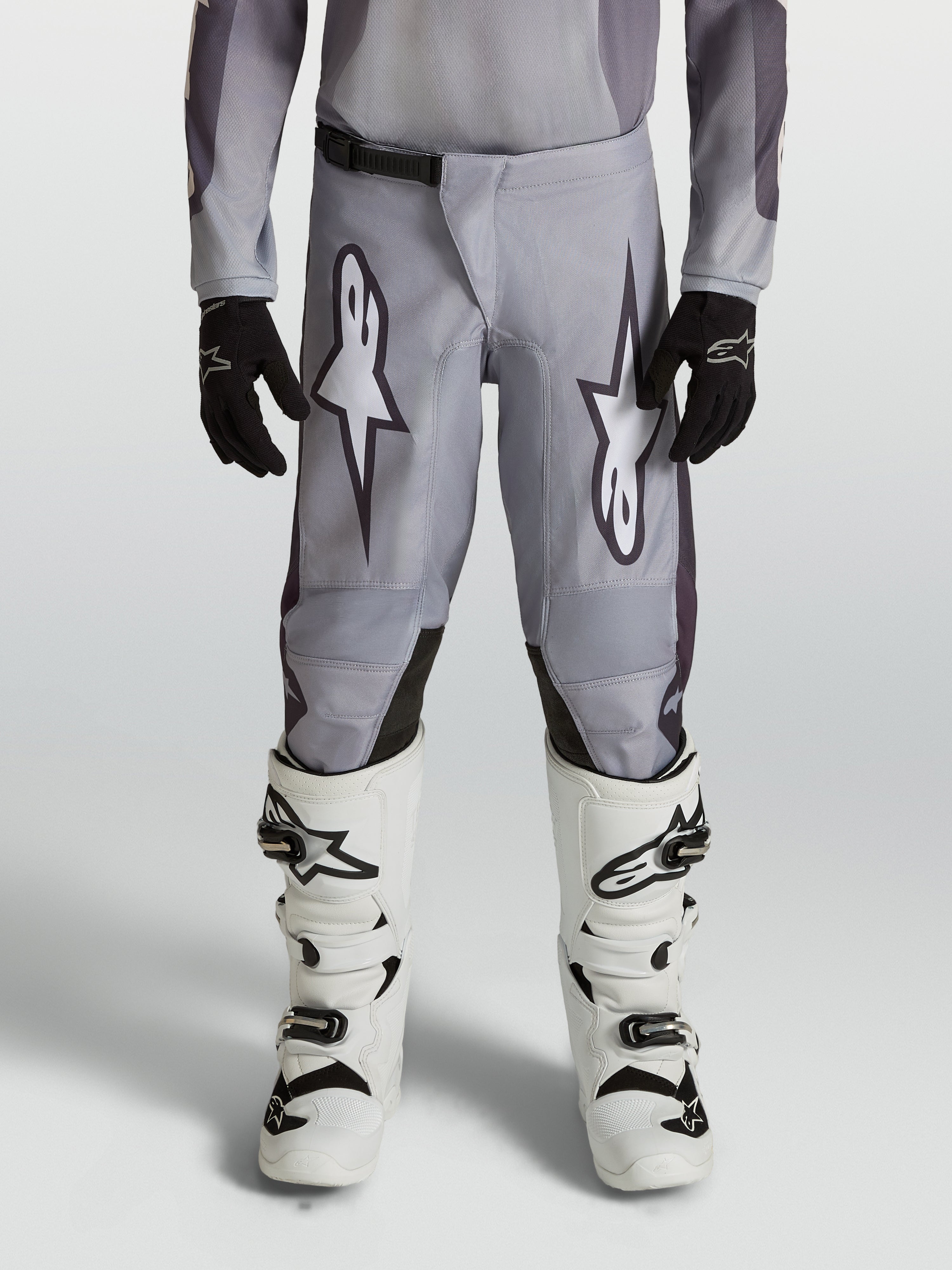 Alpinestars Youth Fluid Amber Pants, durable grey and black motocross pants for young riders in an off-road setting.