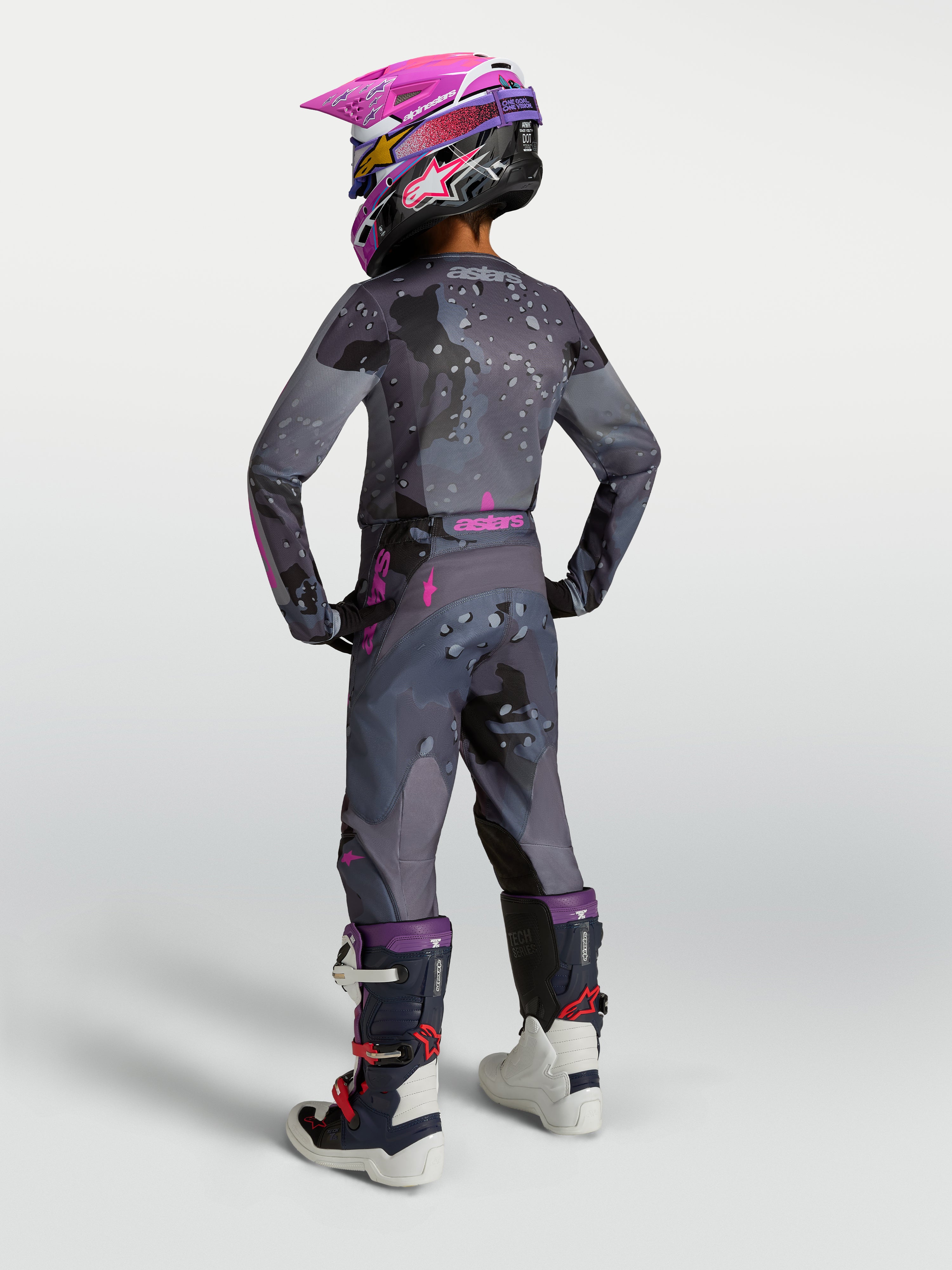 Alpinestars 2027 Youth Fluid Lone Gear Set, gray and pink motocross gear, rear view on rider with helmet and boots.