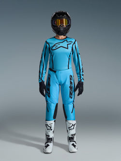 Alpinestars 2026 Stella Fluid Apex Gear Set, Women's Motocross Jersey and Pants, Blue and Black, featuring large star logo on chest, worn with black helmet, tinted goggles, and white boots with black accents, complete off-road racing outfit