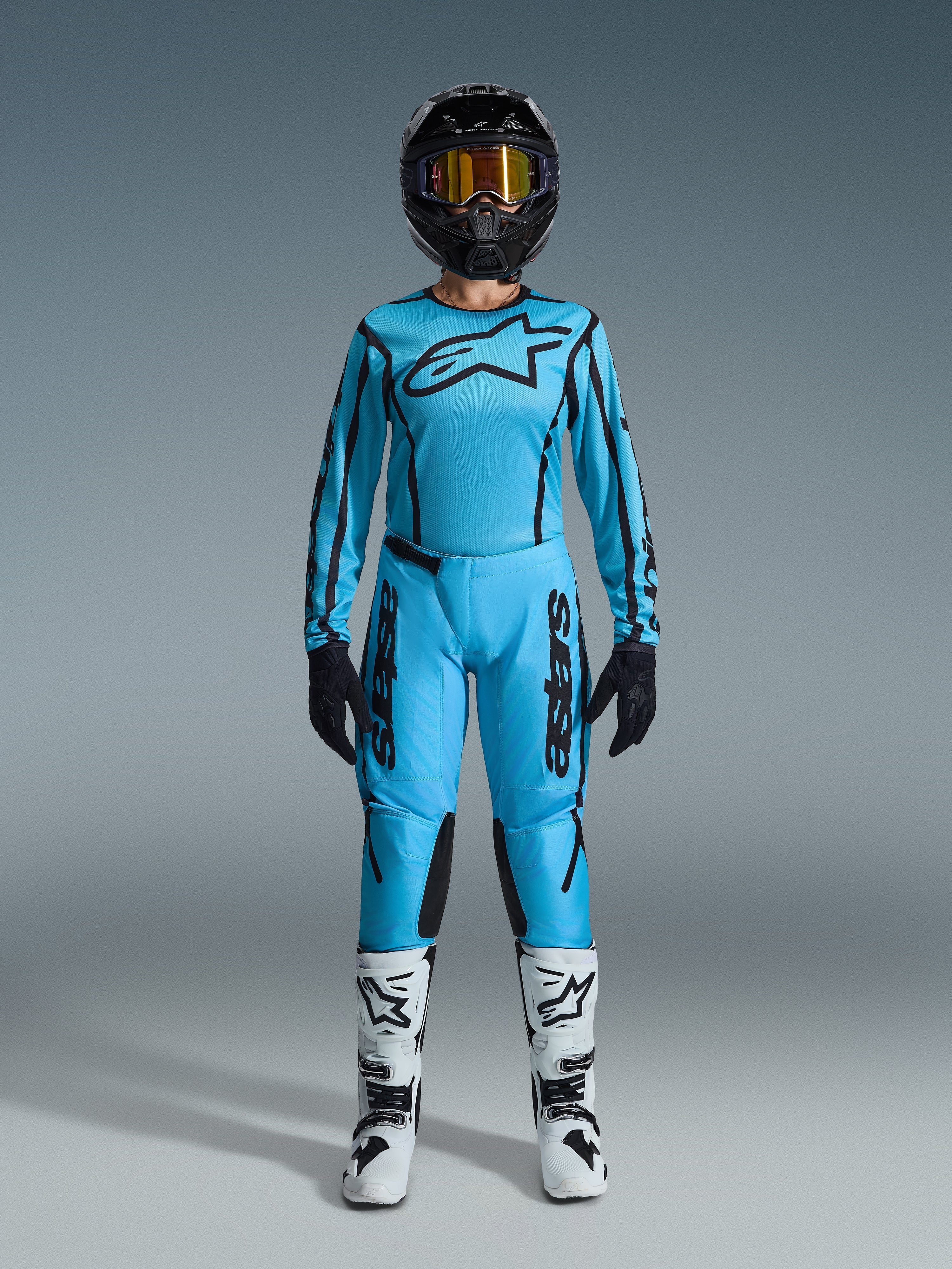Alpinestars 2026 Stella Fluid Apex Gear Set, Damen-Motocross-Jersey und Hose, Blau und Schwarz, mit großem Sternen-Logo auf der Brust, getragen mit schwarzem Helm, getönter Brille und weißen Stiefeln mit schwarzen Akzenten, komplettes Offroad-Rennoutfit