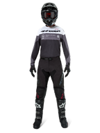 Motocross rider wearing complete racing gear, Pro-Dura Jersey in Black Magnet White with white upper chest and grey accents, paired with black pants, black helmet with dark goggles, white and black boots, and black gloves, coordinated outfit for enduro and off-road racing