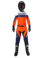 Motocross-Fahrer in kompletter Alpinestars Pro-Dura Ausrüstung, Jersey in Navy, Hot Orange und Weiß, passende Hose in Orange und Navy, schwarze Motocross-Stiefel mit weißen Logos, schwarzer Helm und Handschuhe, koordiniertes Outfit für Offroad-Rennen
