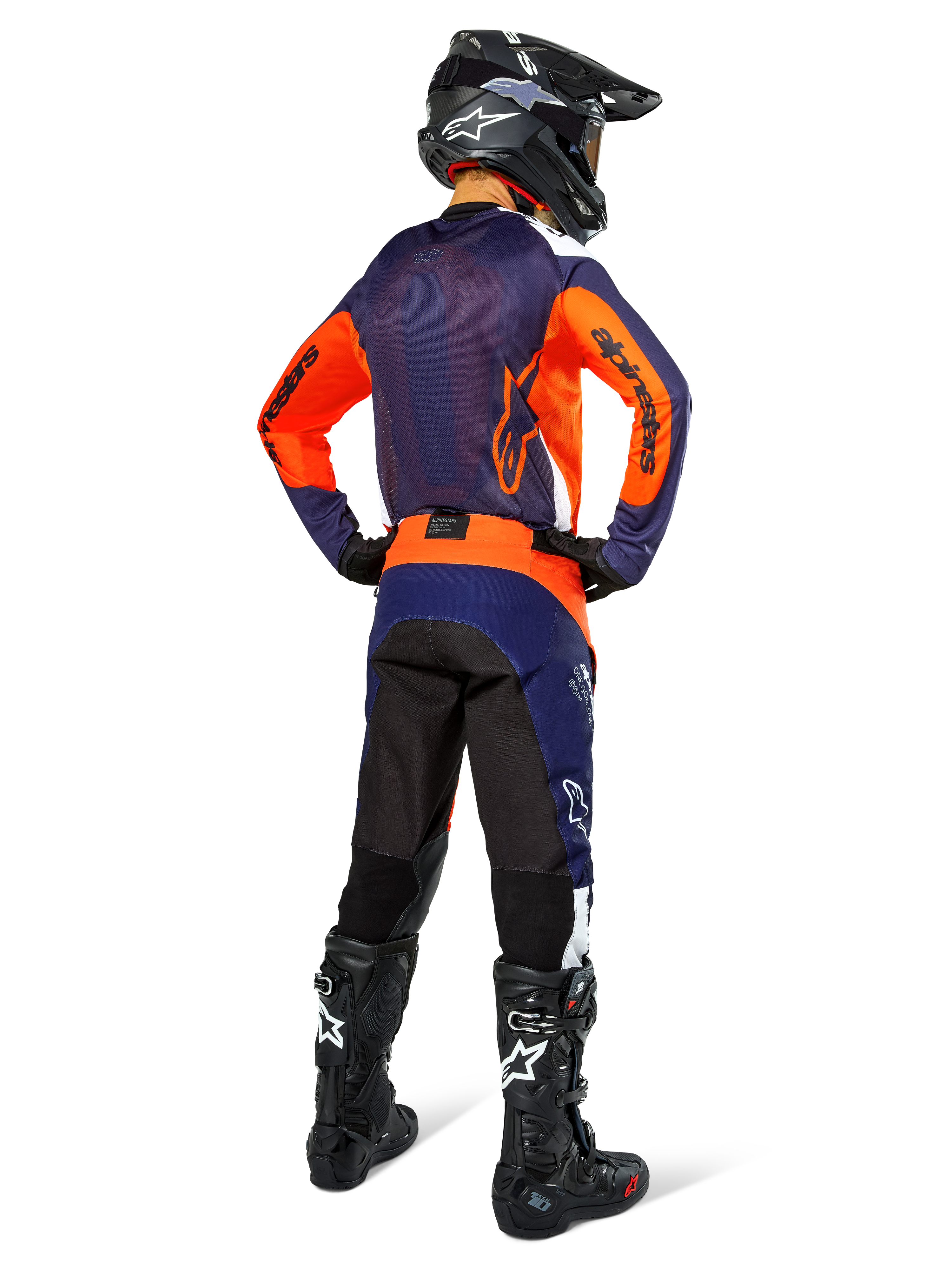 Motocross-Fahrer von hinten im Alpinestars Pro-Dura Trikot, Navy, Hot Orange und Weiß, dazu passende navy- und orangefarbene Hose, schwarzer Helm und schwarze Stiefel, mit atmungsaktivem Mesh-Rückeneinsatz und verlängertem Rücken, abgestimmte Ausrüstung für Enduro-Rennen