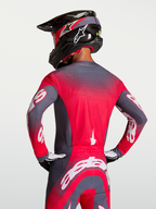 Alpinestars Supertech Hiten AFD Trikot, Motocross-Renntrikot in Grau und Rot, mit Belüftung am Rücken, getragen von einem Fahrer.