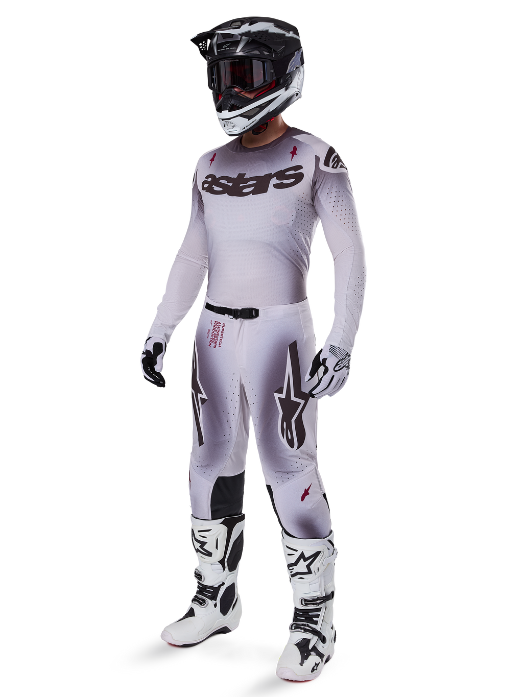 Motocross-Fahrer im Alpinestars 2025 Supertech Maker Trikot in Silber und Schwarz, passende silber-schwarze Hose, schwarz-weißer Helm mit schwarzer Brille, weiß-schwarze Stiefel und koordinierte Handschuhe, professionelles Farbverlauf-Design für den Offroad-Rennsport