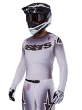 Alpinestars 2025 Supertech Maker Jersey, Motocross-Renntrikot, Silber-Schwarz-Farbverlauf, atmungsaktives Stretch-Mesh mit lasergeschnittenen Perforationen, getragen mit passender Hose und Helm, mit „astars“-Branding, komplette professionelle Offroad-Ausrüstung