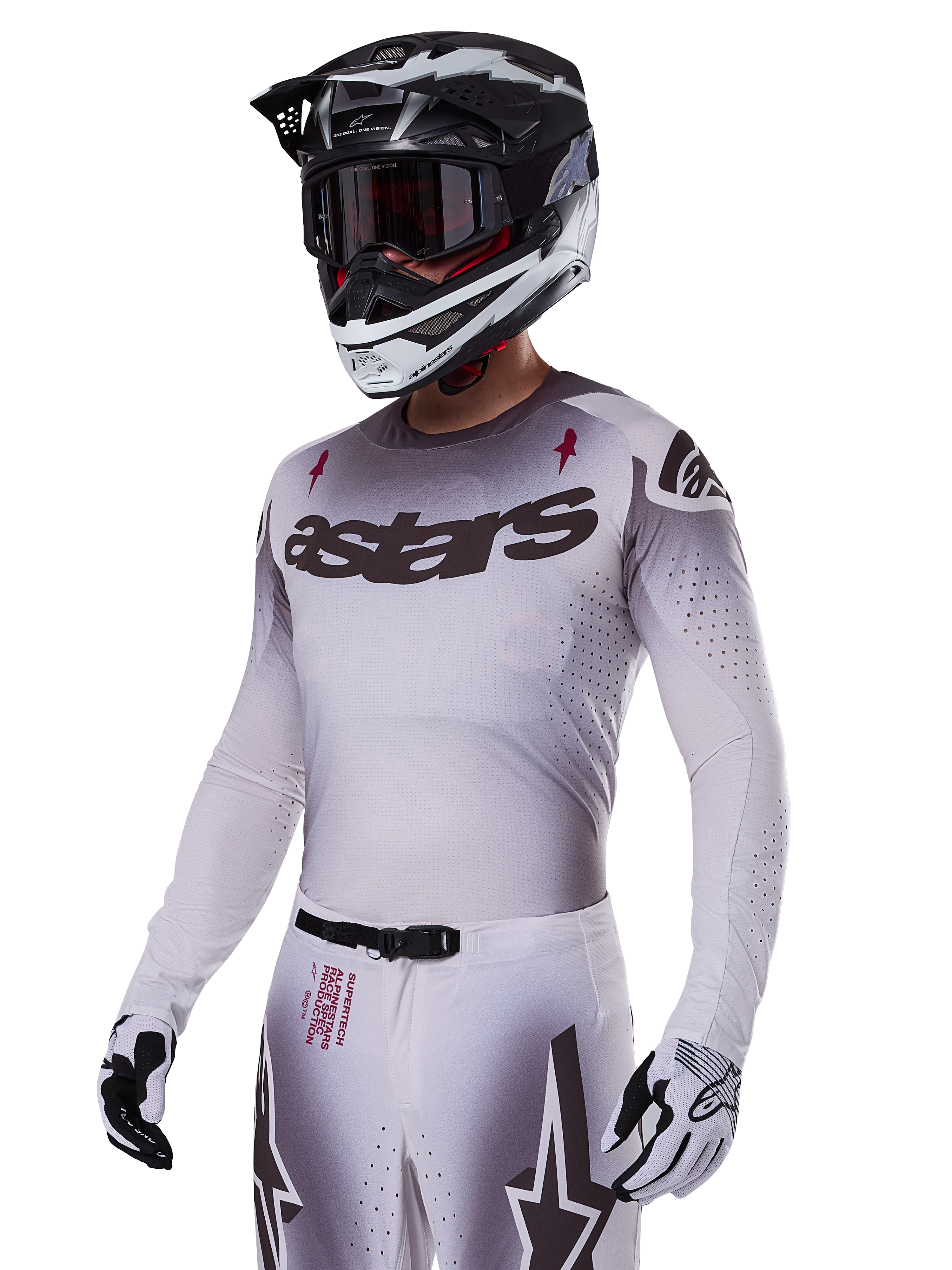 Alpinestars 2025 Supertech Maker Jersey, Motocross-Renntrikot, Silber-Schwarz-Farbverlauf, atmungsaktives Stretch-Mesh mit lasergeschnittenen Perforationen, getragen mit passender Hose und Helm, mit „astars“-Branding, komplette professionelle Offroad-Ausrüstung