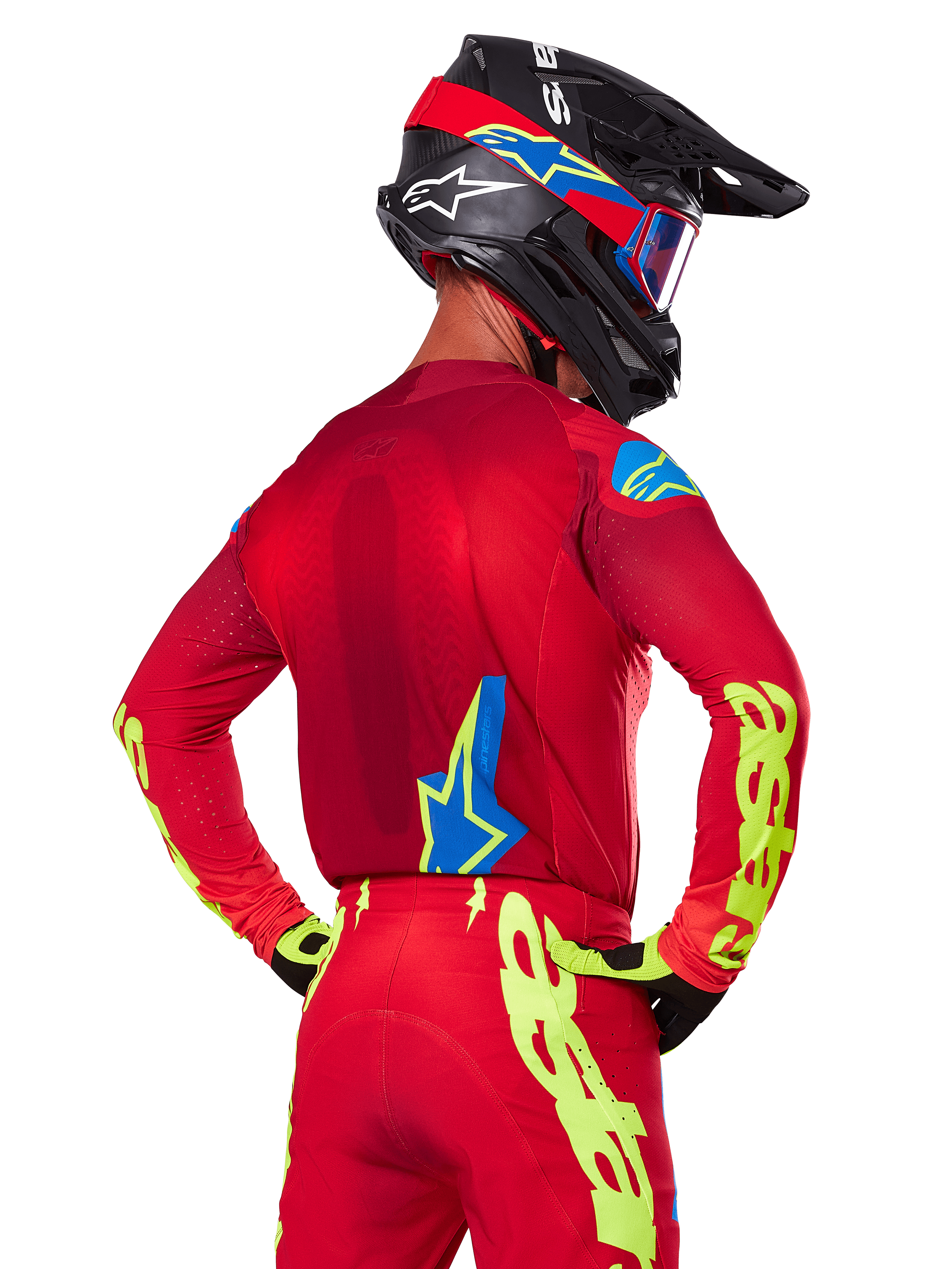 Rückansicht eines Motocross-Fahrers im Alpinestars 2025 Supertech Maker Gear Set in Rot, mit einem roten Trikot mit neongelbem Branding an den Ärmeln, einer passenden roten Hose, einem schwarzen Helm mit blauen und roten Akzenten sowie dazu passenden schwarz-gelben Handschuhen.