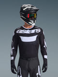 Alpinestars 2026 Racer Air Riway Jersey, Black and White motocross jersey with 'astars' branding, worn by a rider with matching black helmet, goggles, and pants, featuring breathable mesh panels for off-road racing.