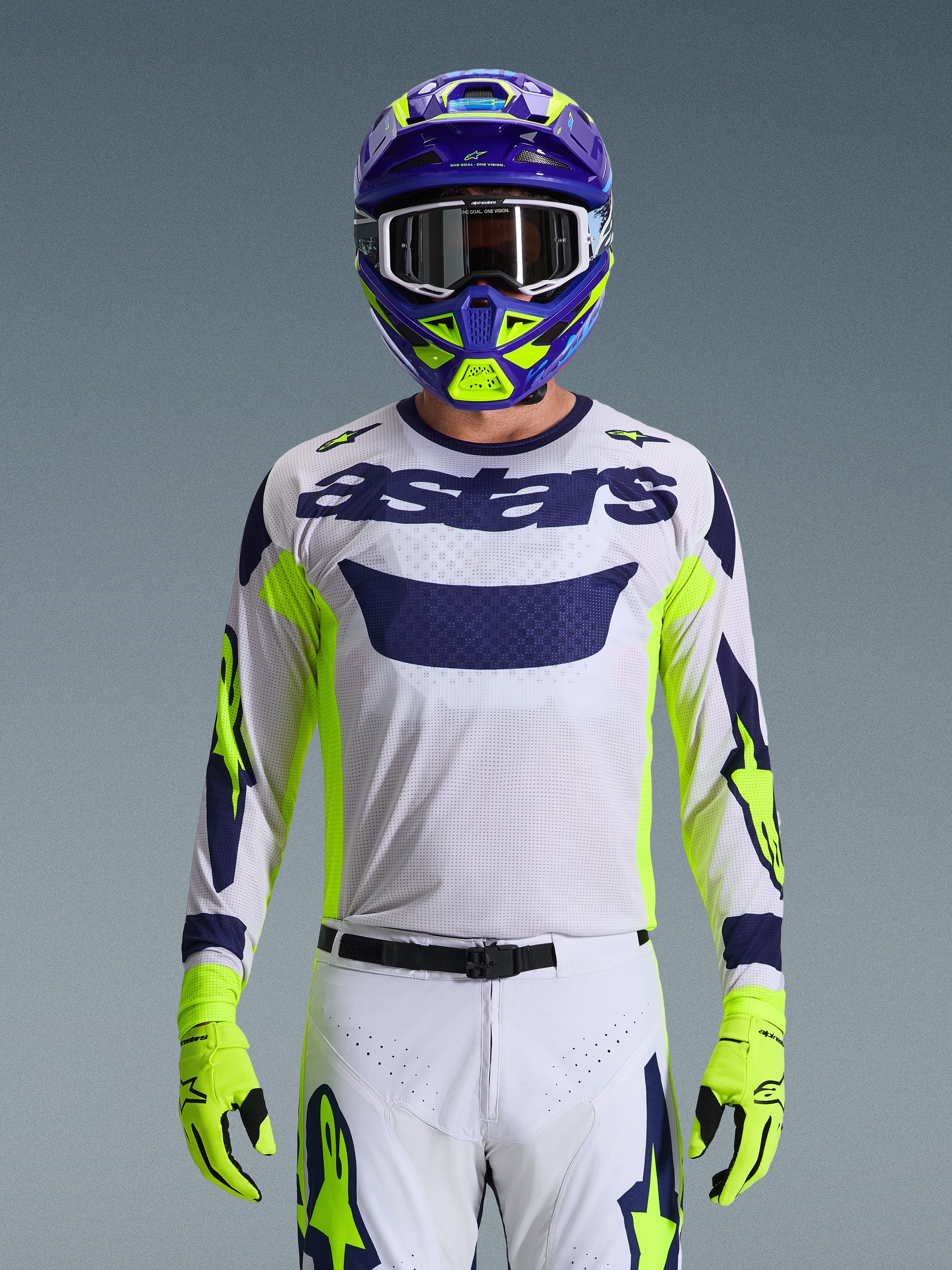 Alpinestars 2026 Racer Air Riway Ausrüstungsset, Motocross-Fahrer, weißes Mesh-Trikot mit navyblauem „astars“-Branding und neongelben Akzenten, passende weiße Hose mit navyblauen und neongelben Grafiken, neongelbe Handschuhe, lila und neongelber Helm mit weißer Brille, Studioaufnahme einer kompletten Offroad-Rennausrüstung
