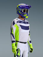 Motocross-Fahrer im Alpinestars 2026 Racer Air Riway Trikot, Hellgrau mit Gelb Fluo und blauen Akzenten, kombiniert mit einem passenden blau-gelben Helm und fluo-gelben Handschuhen, mit atmungsaktiver Mesh-Konstruktion und professionellem Renn-Styling für Offroad-Performance.
