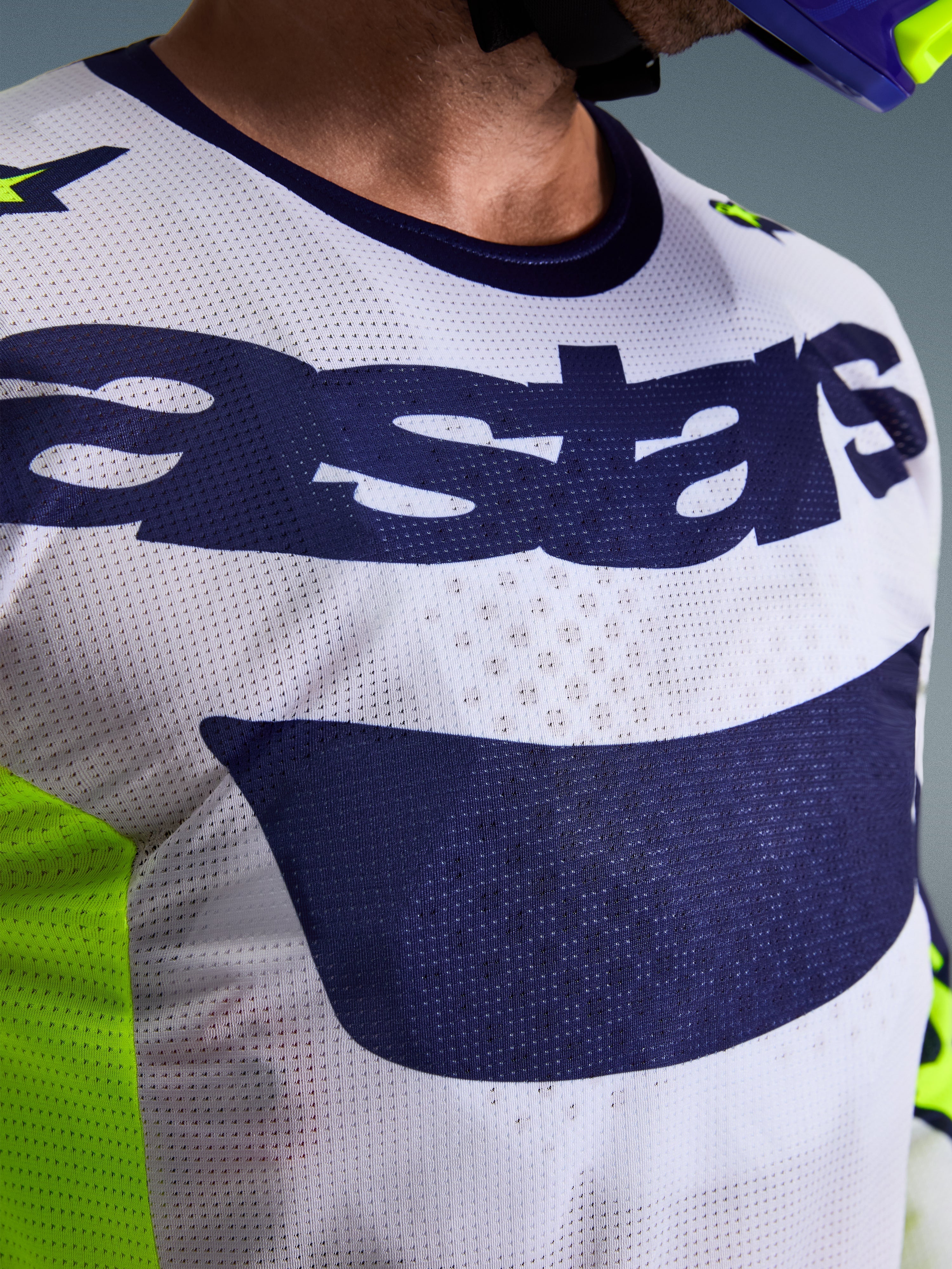 Alpinestars 2026 Racer Air Riway Trikot, Motocross-Trikot, Hellgrau und Marineblau mit fluoreszierendem Gelb, Nahaufnahme der Brust mit „astars“-Logo und perforiertem Mesh-Gewebe, sportliche Passform für Offroad-Fahrten