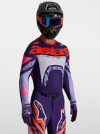 Alpinestars Supertech Dyna Trikot, Motocross-Oberteil für Herren, Lila und Pink Fluo, aus leichtem Stretch-Mesh mit Laserperforationen, getragen von einem Fahrer mit Helm und Handschuhen, professionelle MX-Rennausrüstung