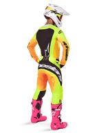 Motocross-Fahrer in der Rückansicht, trägt das Alpinestars 2025 Techstar Melt Trikot mit leuchtendem gelb-orangefarbenem Farbverlauf und schwarzen Abschnitten, passende Motocross-Hose, leuchtend pinke Stiefel und weißer Helm, athletische Passform für Offroad-Wettbewerbe.
