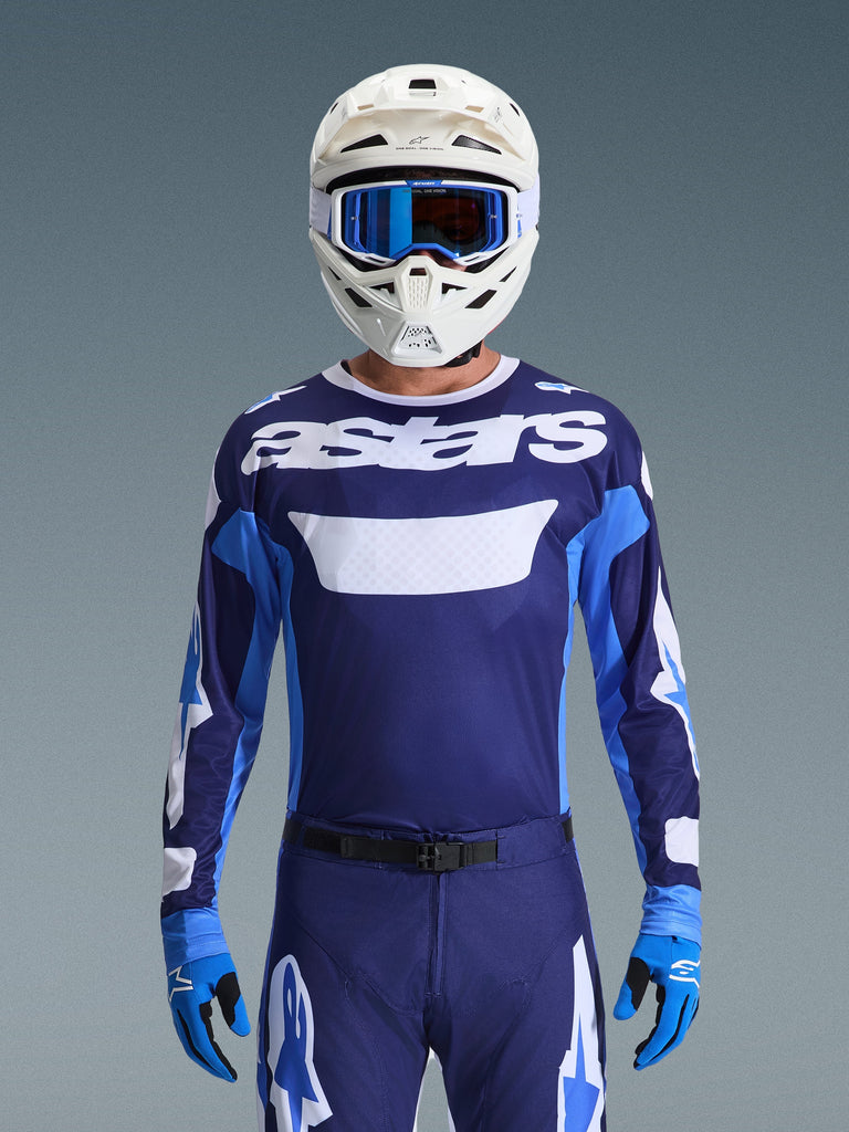 Motocross-Fahrer mit Alpinestars 2026 Racer Riway Jersey, UCLA Blau und Weiß mit weißem „astars“-Logo auf der Brust, weißer Helm mit blauer Brille, passende Motocross-Hose und blaue Handschuhe, abgestimmte Offroad-Rennausrüstung
