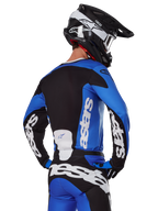 Alpinestars 2025 Racer Veil Ausrüstungsset, Motocross-Ausrüstung, Blau, Schwarz und Weiß, Rückansicht eines Fahrers in Trikot und Hose mit markantem Branding, schwarz-weißer Helm, abgestimmtes Outfit für den Offroad-Rennsport