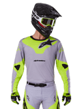 Alpinestars 2025 Racer Veil Jersey, Motocross Jersey, Gray and Neon Yellow, long-sleeve design with black Alpinestars logos, shown as part of a complete racing gear set with matching pants, black helmet, and gloves.