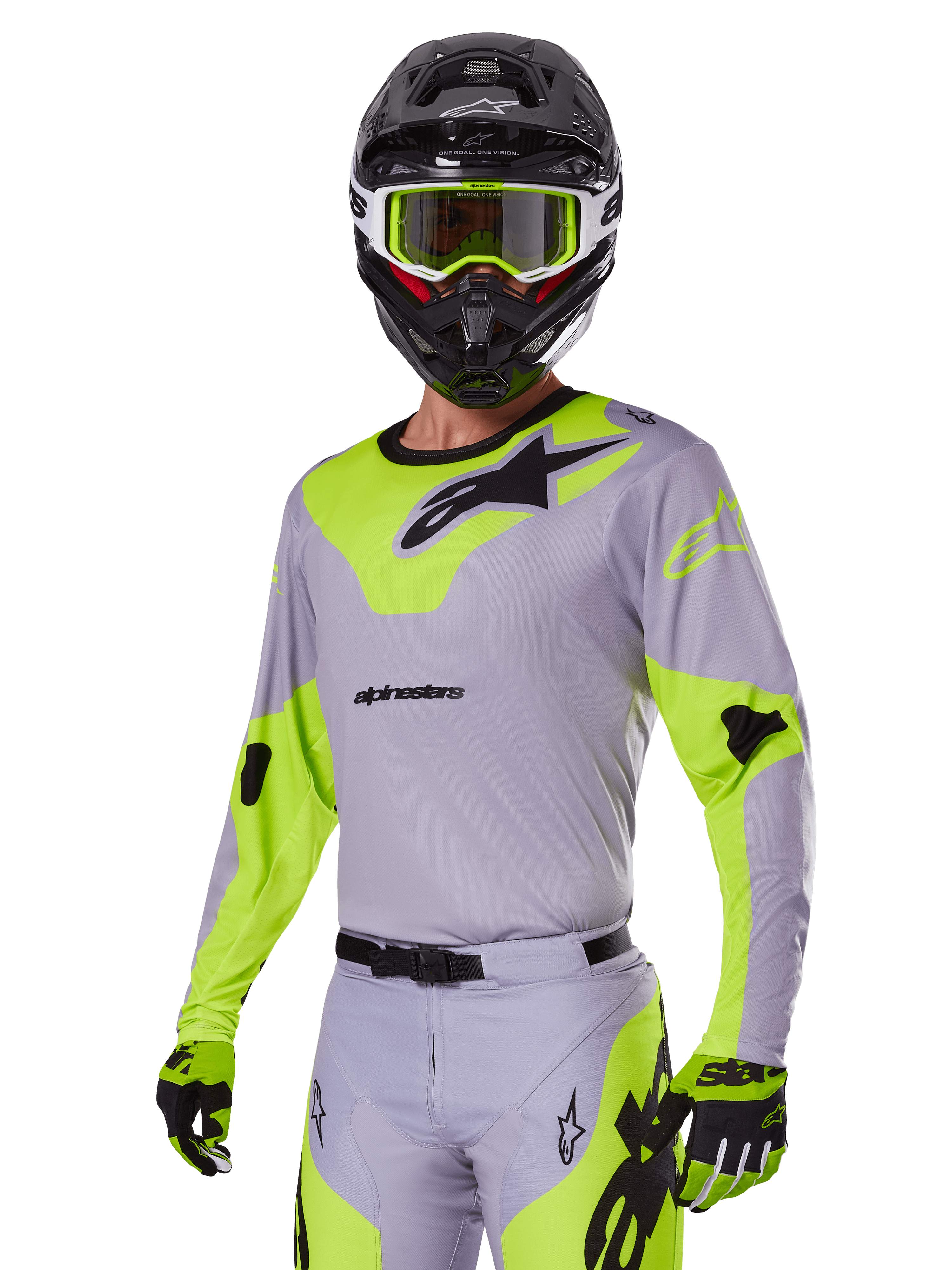 Motocross-Fahrer im Alpinestars 2025 Racer Veil Ausrüstungsset in Grau und Neongrün, hellgraues Trikot und Hose mit markanten neongelb-grünen Einsätzen und schwarzen Alpinestars-Logos, kombiniert mit passenden Handschuhen und einem schwarzen Helm mit neongrüner Brille, professionelle Offroad-Rennbekleidung.