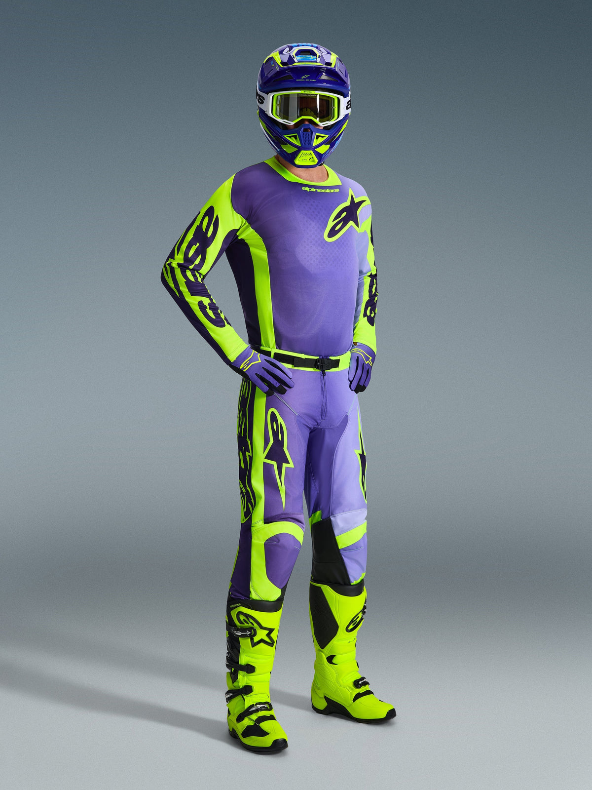 Motocross rider wearing a complete Alpinestars gear set, featuring the 2026 Racer Portl Jersey and matching pants in Purple and Yellow Fluo, coordinated with a matching helmet, goggles, and purple gloves, finished with bright fluo yellow off-road boots, professional racing outfit for motocross performance.