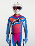 Alpinestars Techstar Maven Trikot, Motocross-Trikot für Herren, Blau, Koralle und Weiß, athletische Passform, feuchtigkeitsableitendes Stretchmaterial, getragen mit Helm und Handschuhen.
