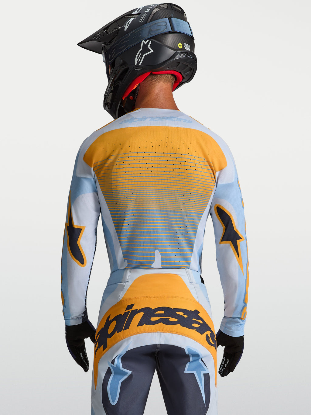 Alpinestars Techstar Maven Trikot, Motocross-Trikot für Herren, Blau und Orange, Rückansicht mit lasergeschnittener Belüftung, getragen von einem Fahrer mit Helm, ideal für MX und Enduro