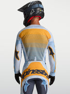 Alpinestars Techstar Maven Trikot, Motocross-Trikot für Herren, Blau und Orange, Rückansicht mit lasergeschnittener Belüftung, getragen von einem Fahrer mit Helm, ideal für MX und Enduro