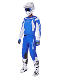 Motocross-Fahrer trägt das komplette 2025 Fluid Haul Gear Set, blau-weißes Trikot und Hose mit Alpinestars-Branding, weißer Helm mit blauer Brille, weiße Stiefel und blaue Handschuhe, koordiniertes Racing-Outfit für Offroad-Motocross.