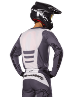 Motocross rider from behind wearing Alpinestars 2025 Fluid Haul Gear Set, Gray and White jersey and pants, black helmet with white graphics, yellow goggles, coordinated motocross racing outfit