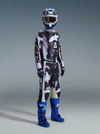 Alpinestars 2026 Racer Lahnd Gear Set, Motocross-Fahrer mit schwarz-weiß gemustertem Jersey und Hose in abstraktem, verwittertem Design, großes weißes Alpinestars-Logo, kombiniert mit leuchtend blau-violetten Stiefeln und einem blau-weißen Helm, komplette professionelle Offroad-Rennausrüstung.
