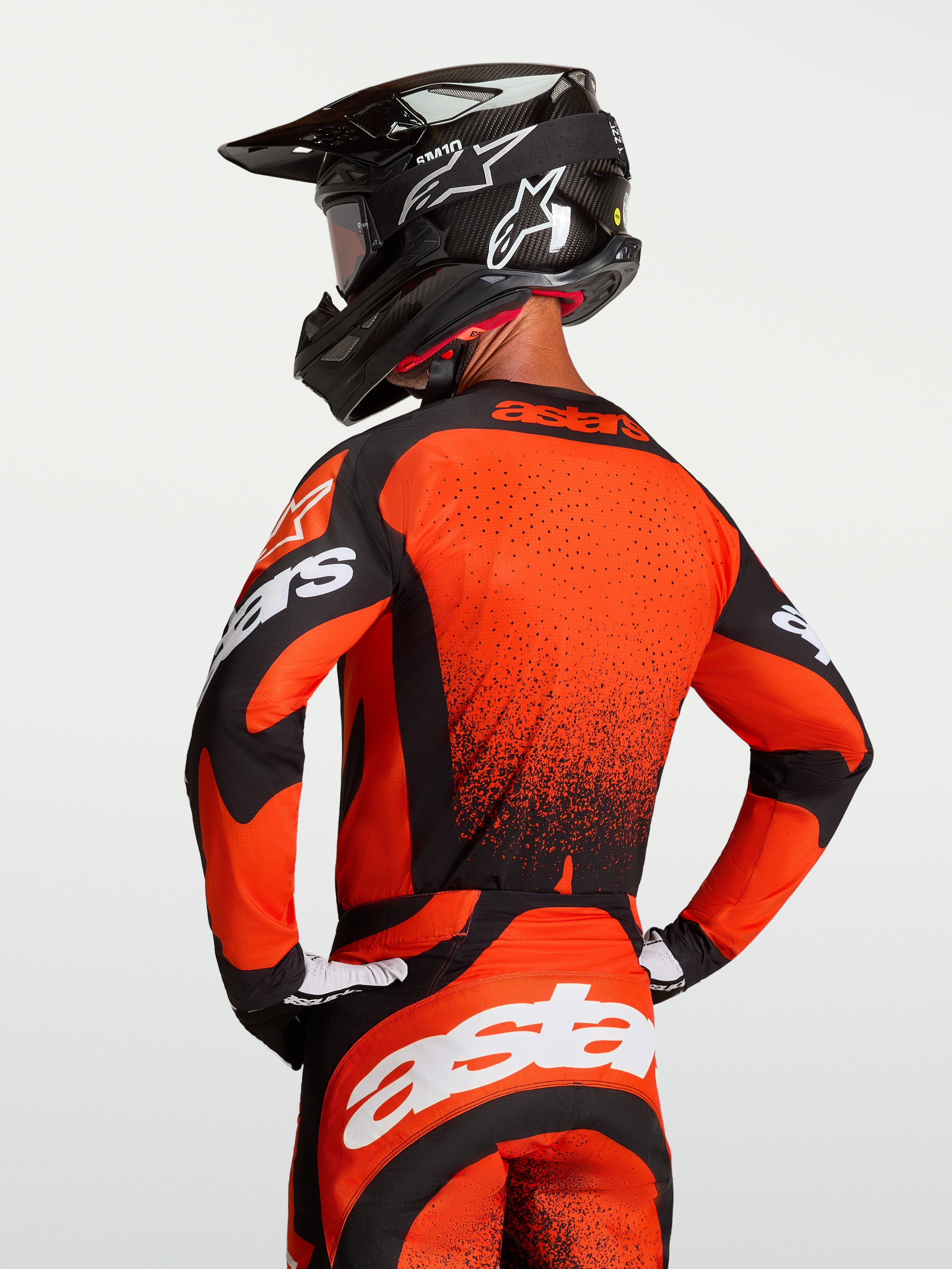 Alpinestars Techstar Swan Trikot, Motocross-Trikot für Herren, Rot und Schwarz, mit Laserperperforationen und athletischer Passform an einem Model mit Helm.