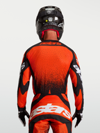 Alpinestars Techstar Swan Trikot, Motocross-Trikot in Rot und Schwarz, Herren-Rückansicht am Model, verlängerter Saum mit Laserperforationen, Racing-Passform für Offroad-Sport.