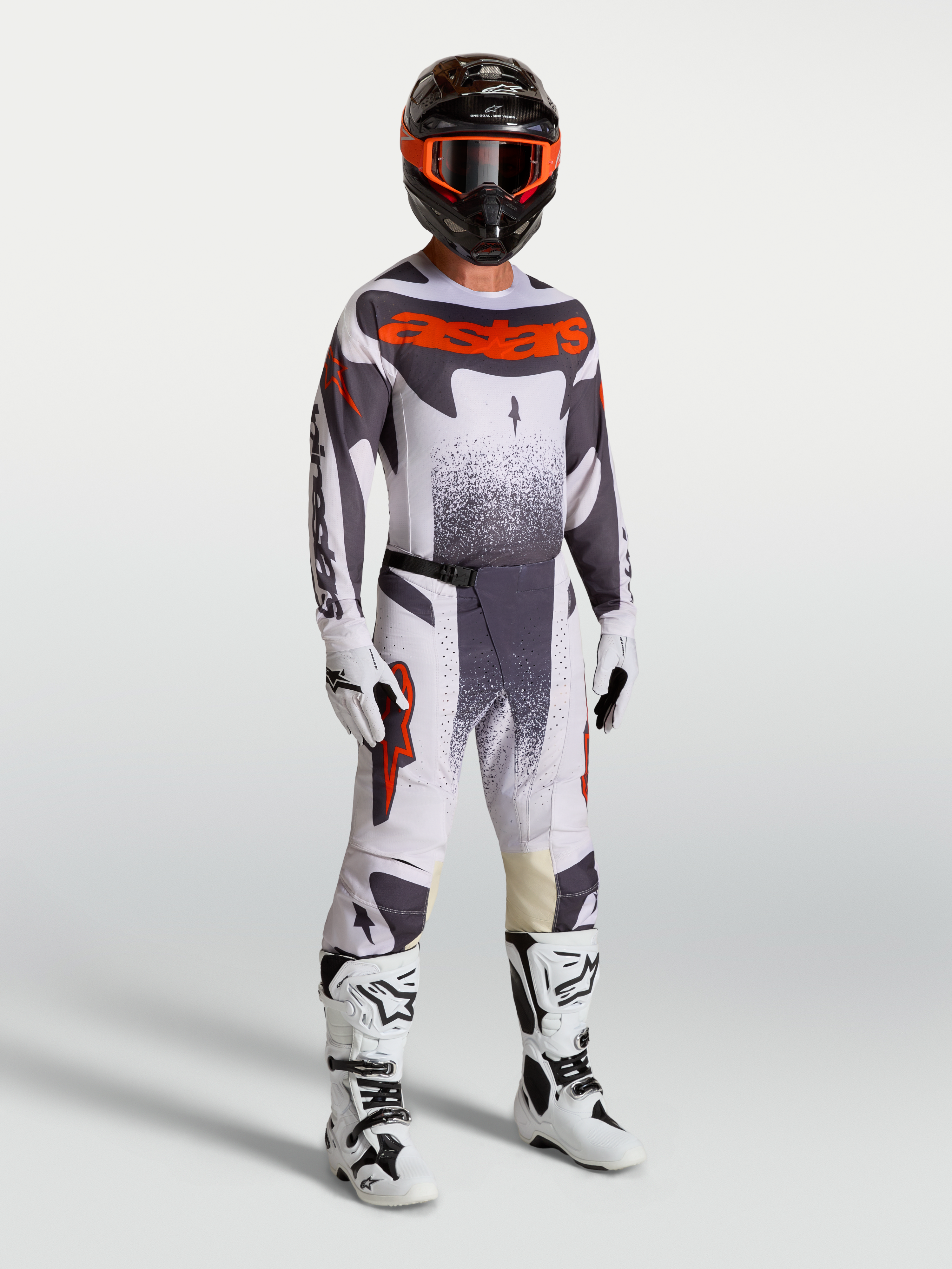 Alpinestars Techstar Swan Trikot und Gear Set am Model, Herren-Motocross-Outfit in Helllila, Grau und fluoreszierendem Rot.