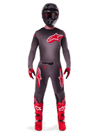 Motocross-Fahrer im Alpinestars 2025 Supertech Lipan Gear Set, Smoke und Bright Red, dunkelgraues Trikot und Hose mit markanten roten Alpinestars-Logos, leuchtend rote Stiefel, schwarzer Helm und rote Handschuhe, professionell abgestimmtes Outfit für den Offroad-Rennsport