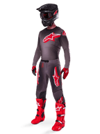 Alpinestars 2025 Supertech Lipan Gear Set, vollständige Motocross-Rennausrüstung, dunkelgraues und rotes Trikot mit großem Sternlogo, passende Hose mit roten Akzenten und Sternengrafiken, rote Handschuhe, leuchtend rote Stiefel mit weißen Schnallen, mattschwarzer Helm mit roter Brille