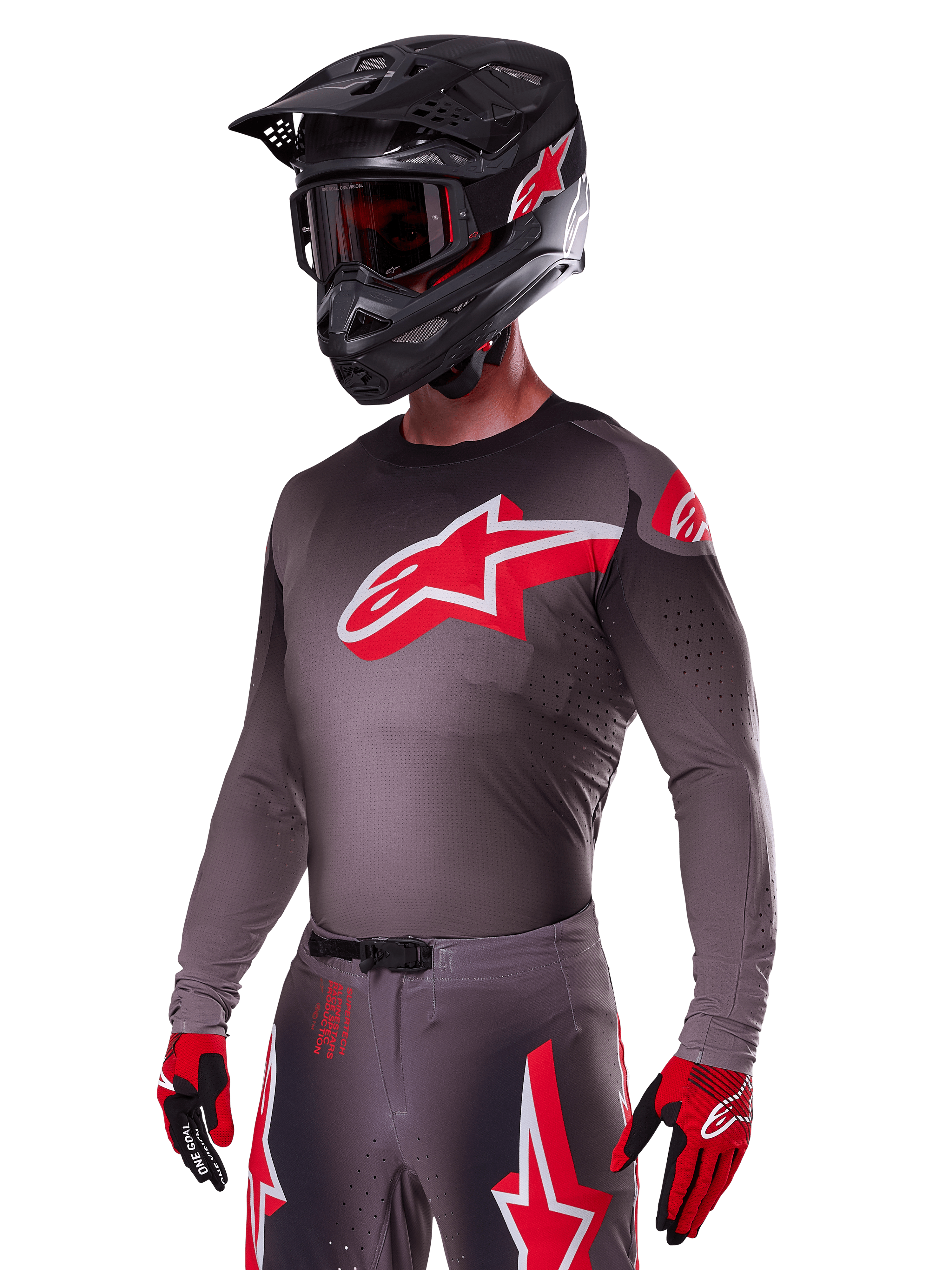 Alpinestars 2025 Supertech Lipan Ausrüstungsset, Motocross-Fahrer in dunkelgrauem Jersey und Hose mit roten und weißen Akzenten, großes rotes Alpinestars-Logo auf der Brust, lasergeschnittene Perforationen zur Belüftung, schwarzer Helm, rote Brille und rot-schwarze Handschuhe